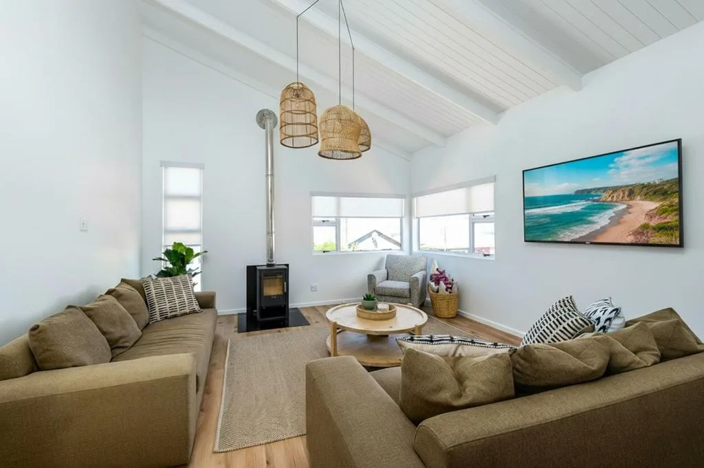 Bright lounge with beige sofas, fireplace, and coastal artwork on wall