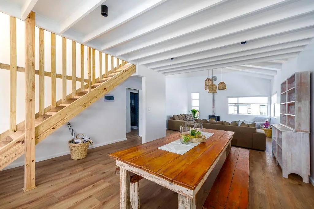 Open-plan lounge with wooden staircase, dining table, and comfortable seating area