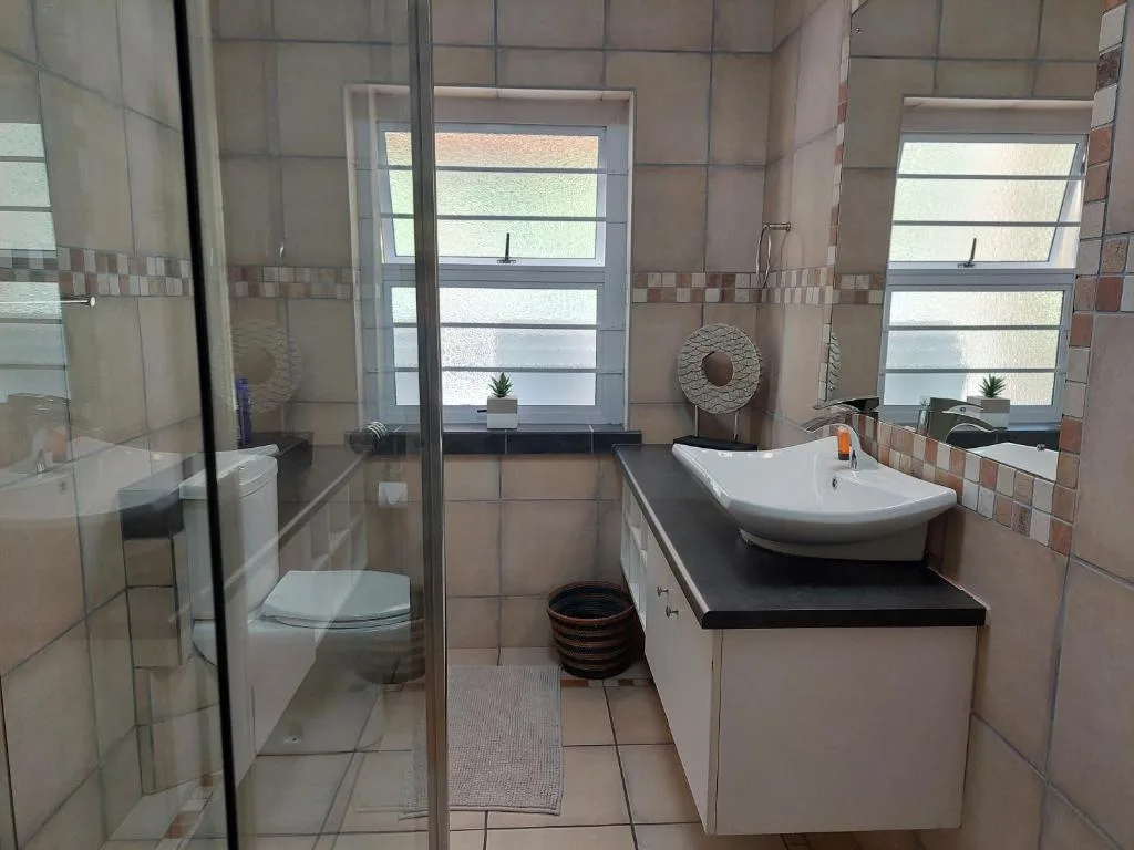 Modern bathroom with curved sink, glass shower enclosure, and windows