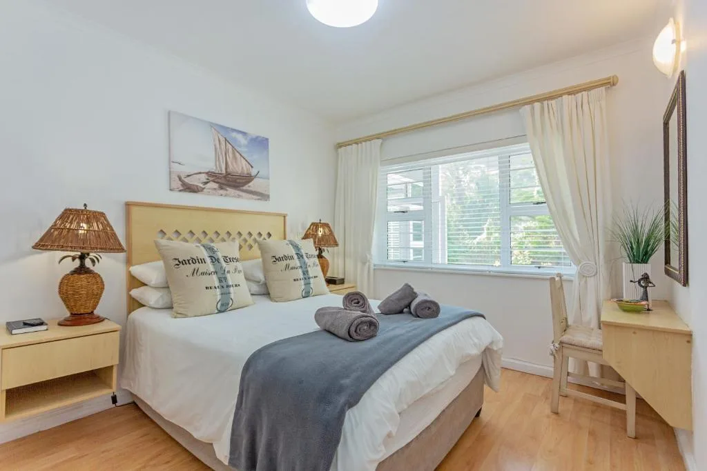 Bright bedroom with queen bed, wicker lamps, and coastal-themed decor