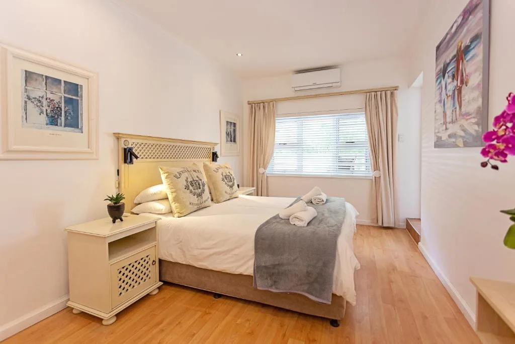 Bright bedroom with queen bed, wooden nightstand, and large windows with curtains