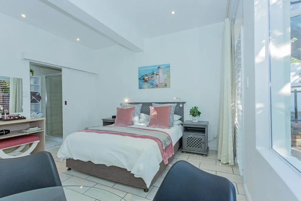 Bright bedroom with queen bed, pink bedding, ensuite bathroom visible