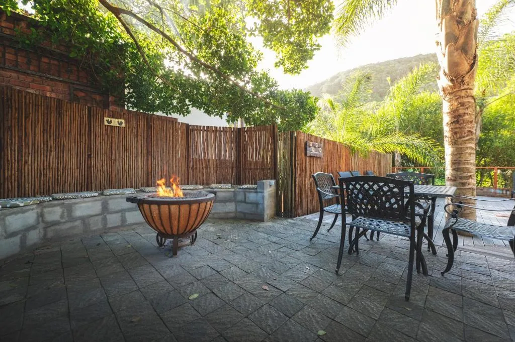 Outdoor patio with firepit, dining table, and mountain views surrounded by lush vegetation