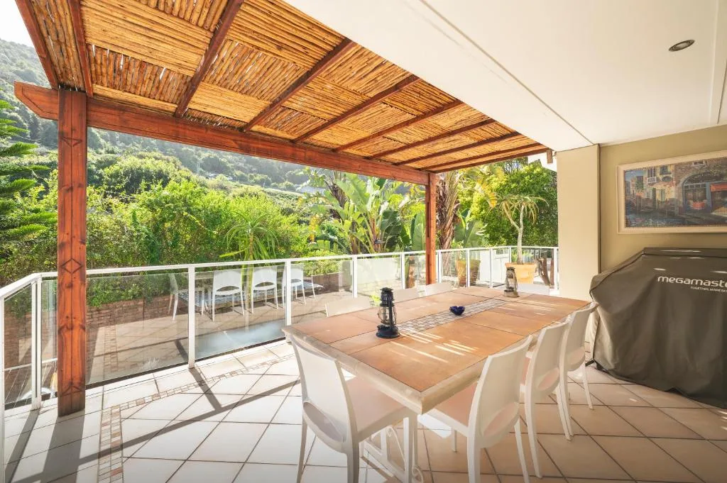 Covered wooden deck with dining table, braai, and mountain views