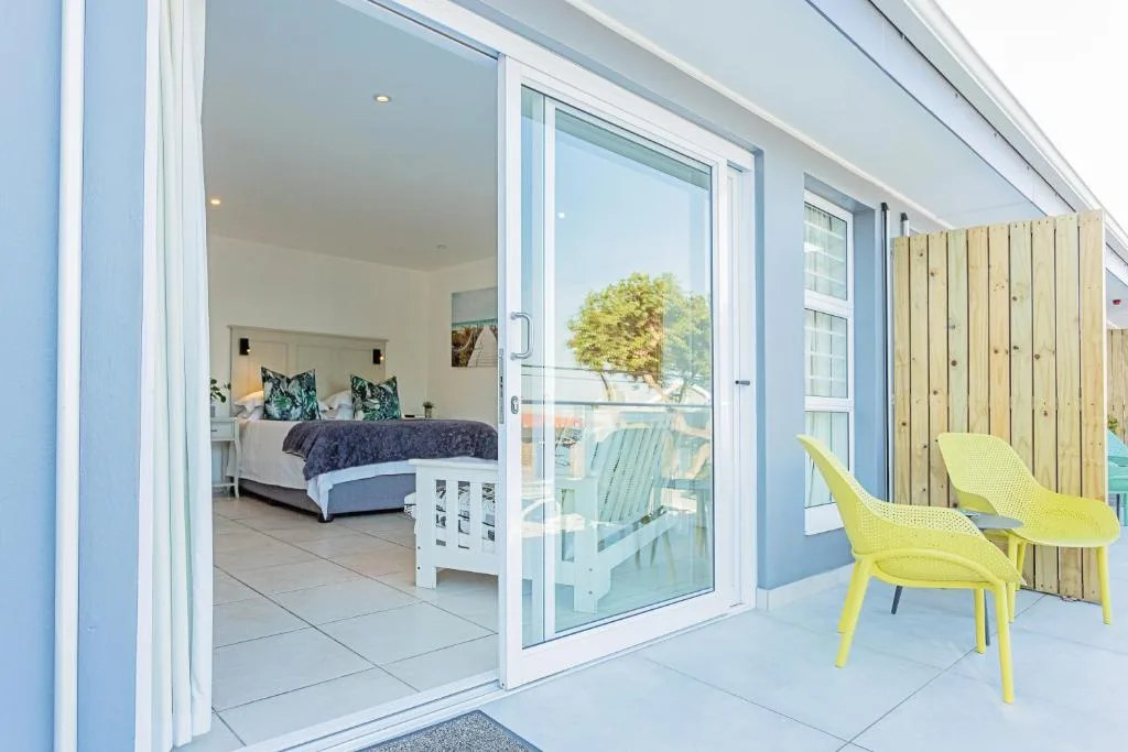 Modern patio with yellow chairs overlooking garden, leading to bright bedroom