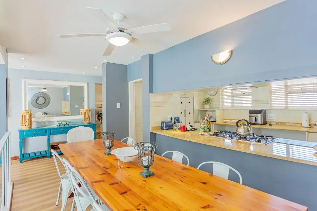 Open-plan dining and kitchen with wooden table and blue accent walls
