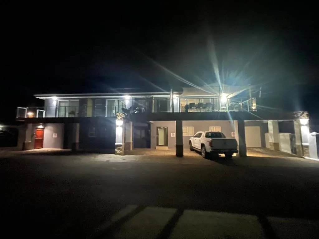 Modern multi-level property facade illuminated at night with parking area