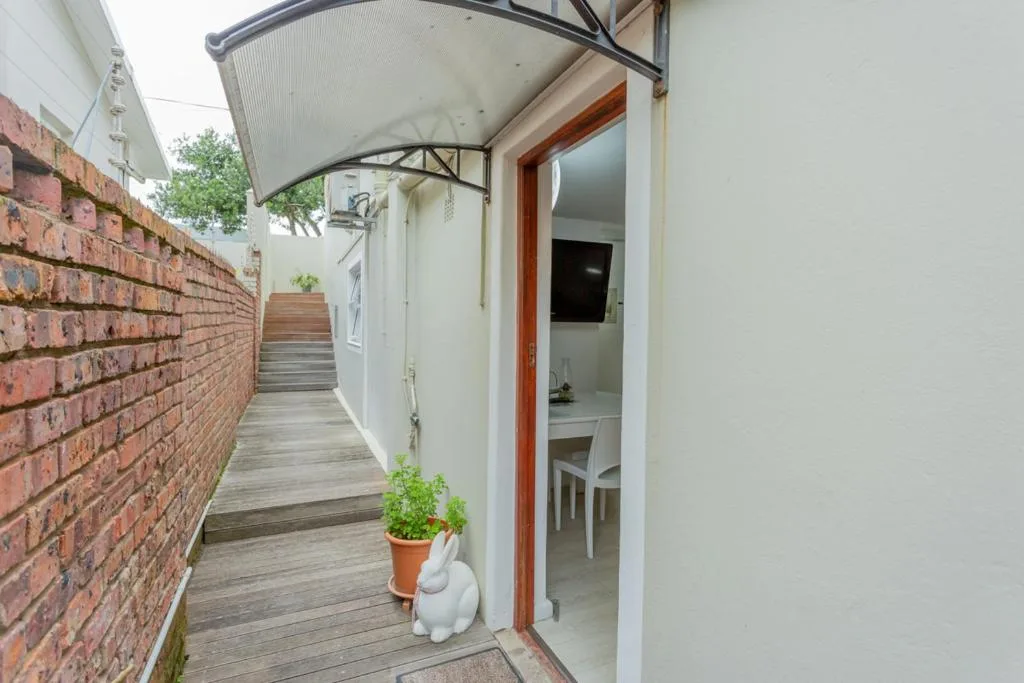 Wooden deck entrance with brick wall and red door leading inside