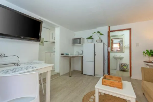 Open-plan kitchen with white cabinetry, refrigerator, and mounted television