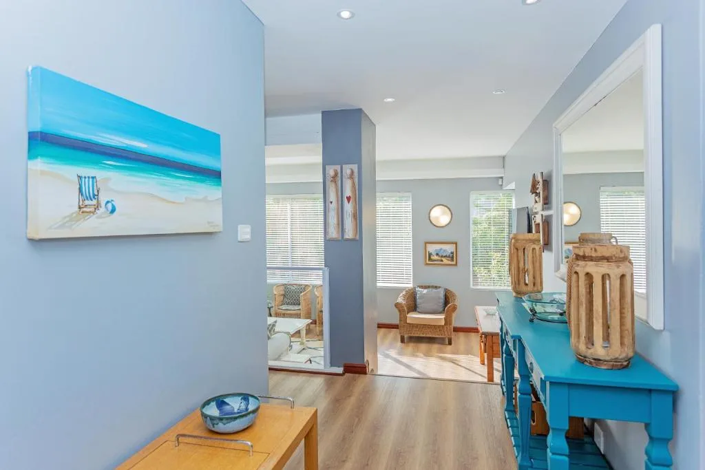 Bright lounge with blue accents, wicker furniture, and coastal artwork