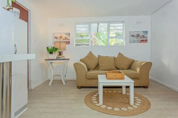 Bright living room with tan sofa, white coffee table, and garden views