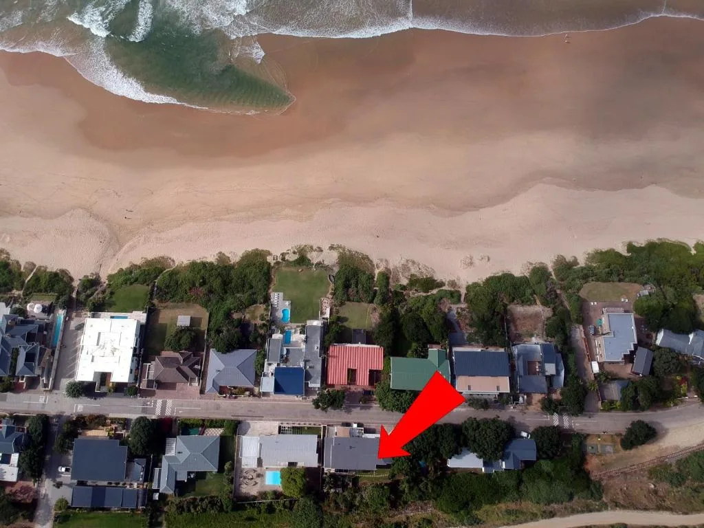 Aerial view of beachfront property with ocean waves and golden sand