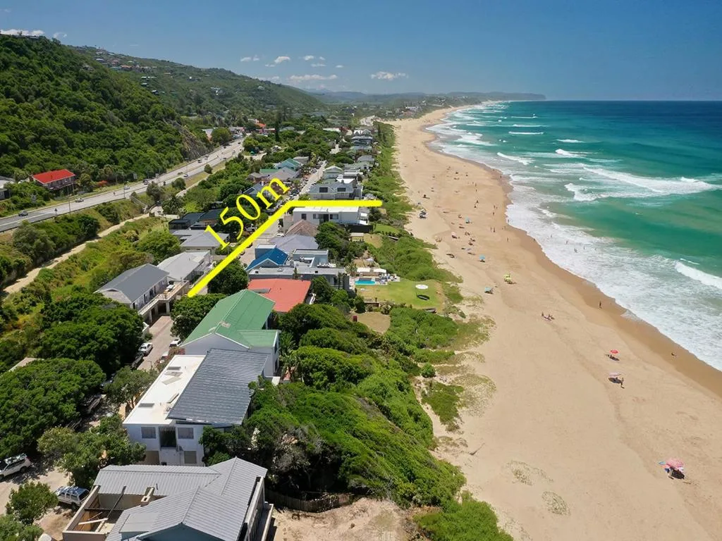 Aerial view of beachfront property with pristine sandy beach and turquoise ocean