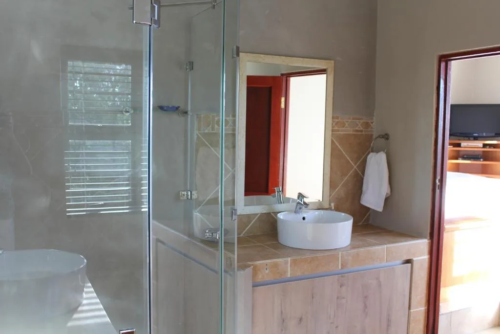 Modern bathroom with round vessel sink, glass shower enclosure, and tiled countertop