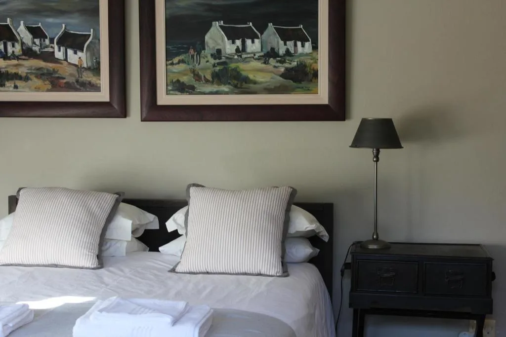 Bedroom with striped pillows, black bedside table, and framed coastal artwork