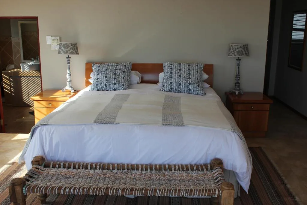 Bright bedroom with queen bed, wooden headboard, patterned pillows, bedside tables