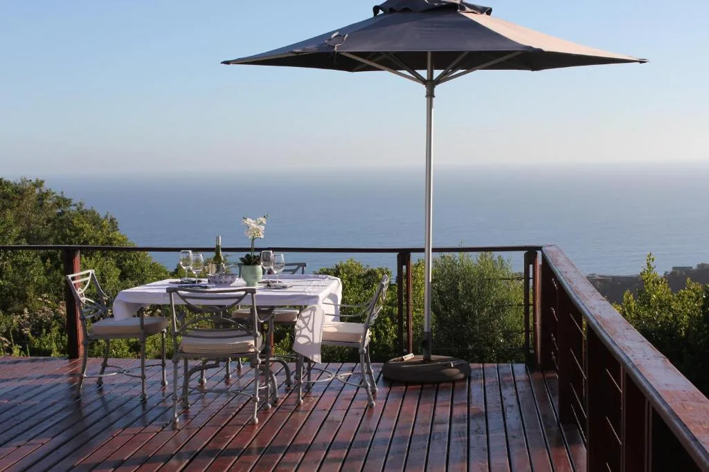 Elevated deck with dining table, umbrella, and expansive ocean views