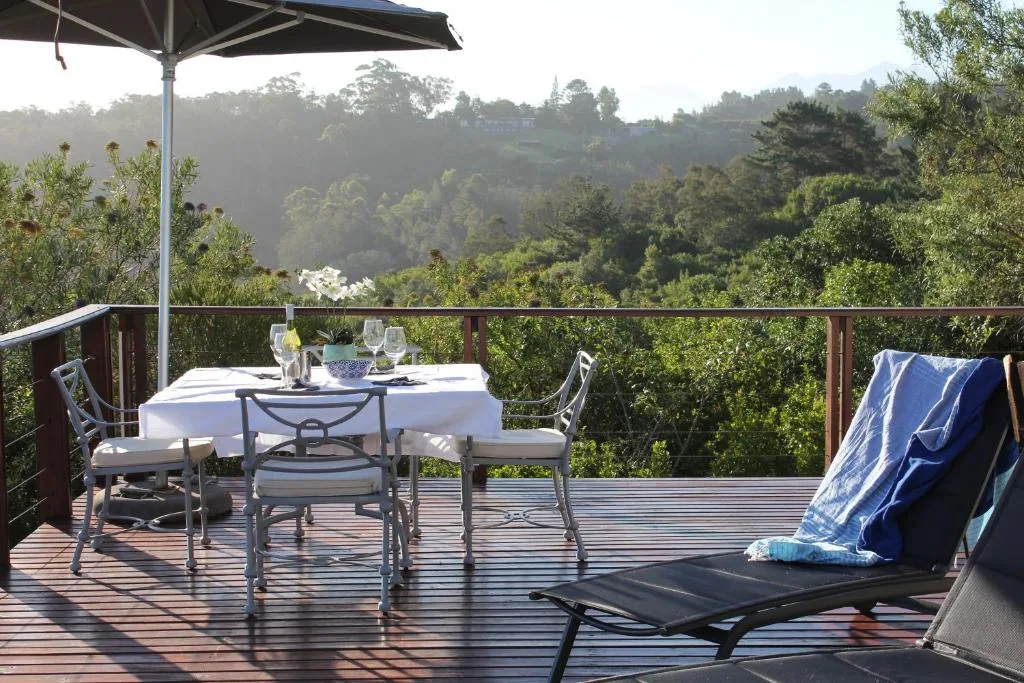 Wooden deck with dining table, chairs, and forest views beyond