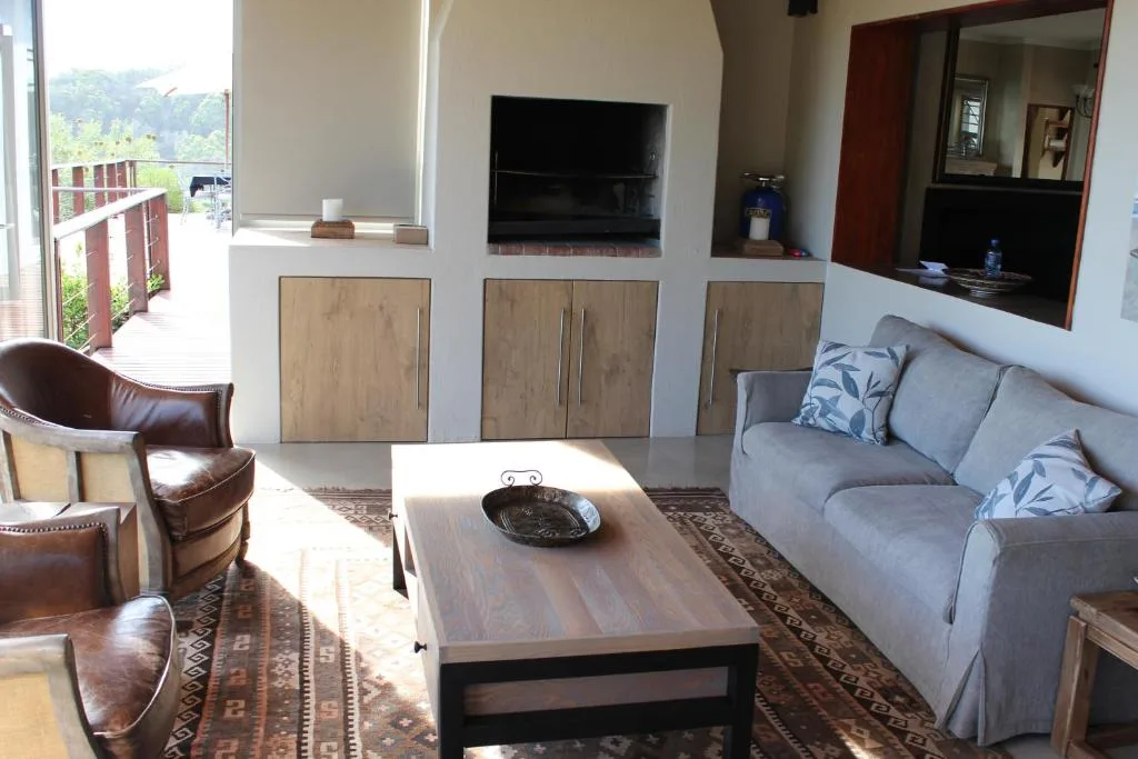 Spacious living room with gray sofa, leather chairs, wooden coffee table, and garden views