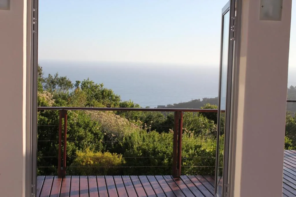Ocean and coastline vista visible beyond lush vegetation from deck