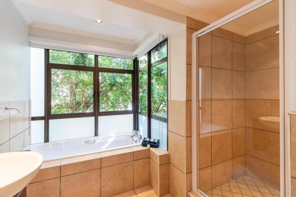 Spacious bathroom with bathtub, shower, and window overlooking greenery