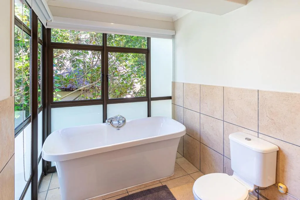 Spacious bathroom with freestanding tub and garden views through windows
