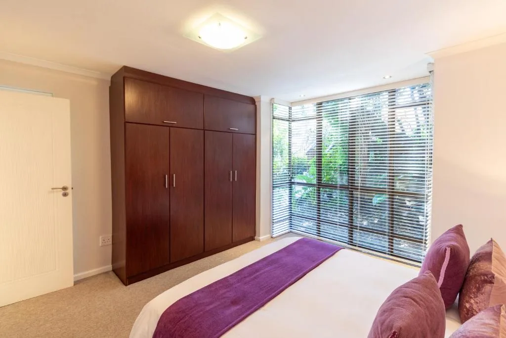 Spacious bedroom with double bed, large wooden wardrobe, and deck access doors