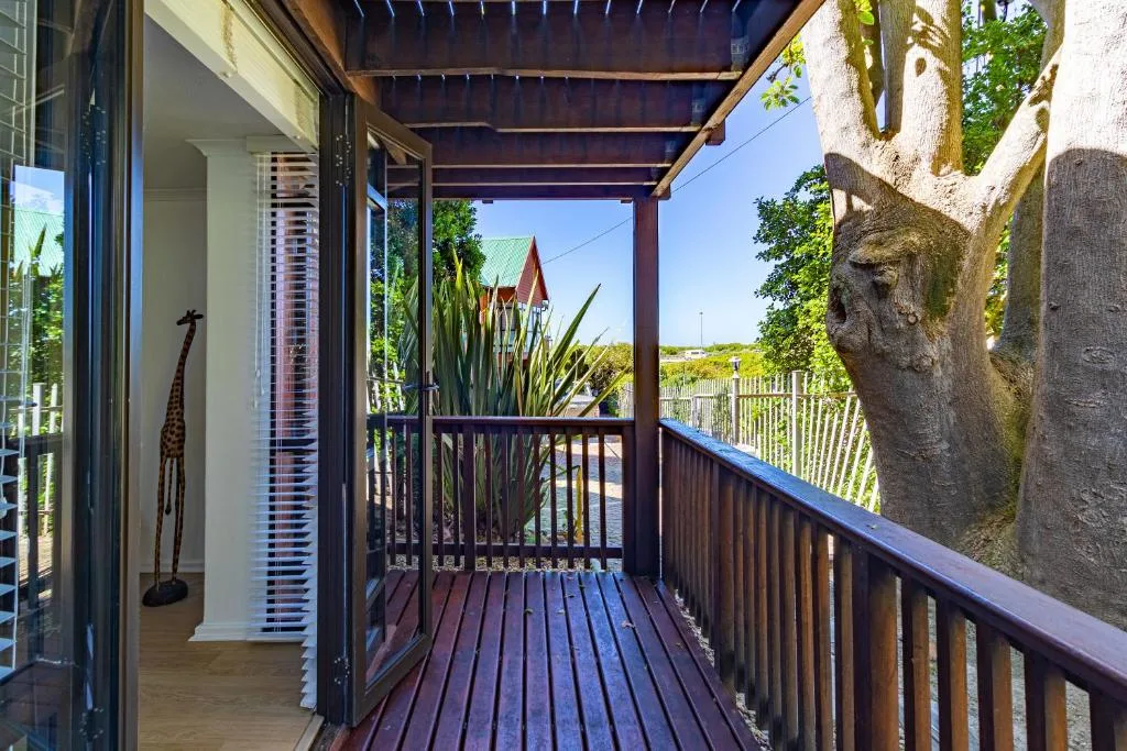 Wooden deck with dark railing overlooking coastal landscape and garden