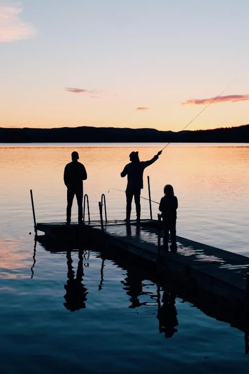 Sunset view over calm water with fishing silhouettes and mountains