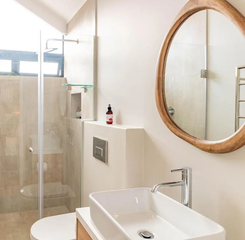 Modern bathroom with vessel sink, round wooden mirror, and glass shower enclosure