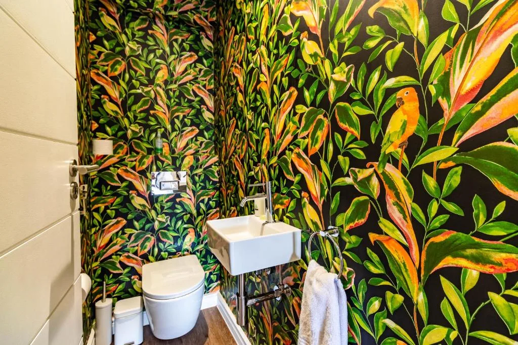 Modern bathroom with vibrant tropical leaf wallpaper and white fixtures