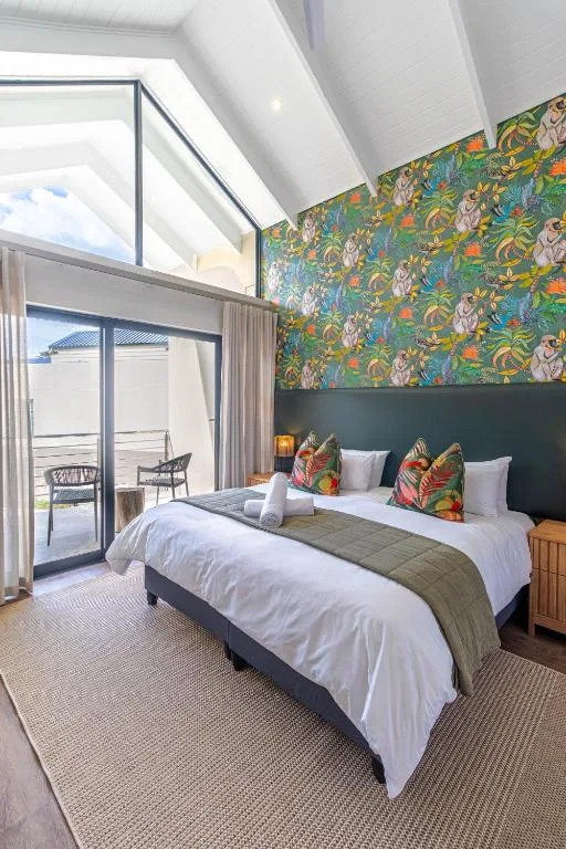 Spacious bedroom with double bed, colorful botanical wallpaper, and deck access