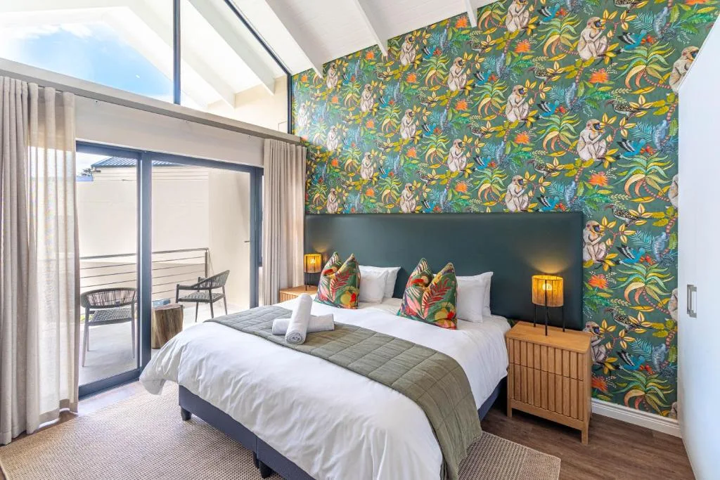 Stylish bedroom with vibrant botanical wallpaper and deck access