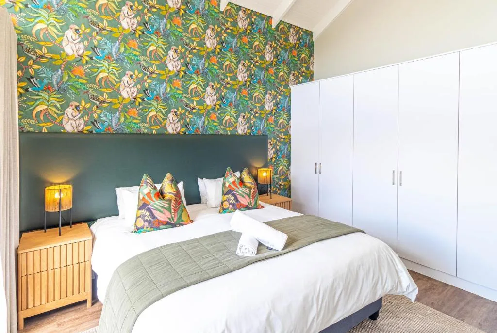 Bright bedroom with colorful tropical wallpaper and patterned cushions on bed