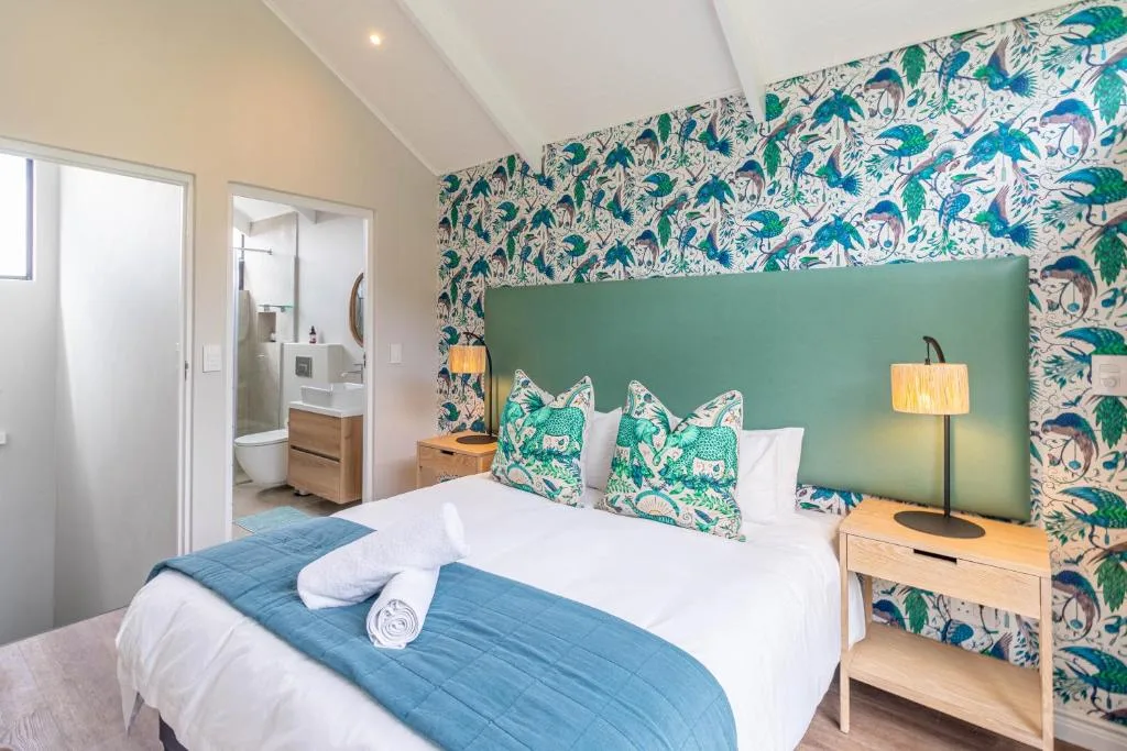 Bright bedroom with patterned wallpaper, green headboard, and en-suite bathroom
