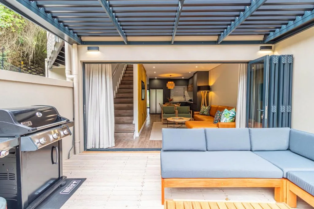 Modern deck with built-in seating, braai grill, and open indoor living space