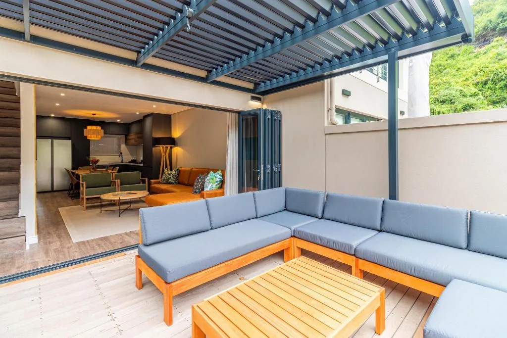 Modern outdoor patio with comfortable seating and pergola overlooking interior lounge