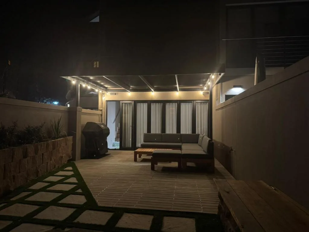 Illuminated outdoor patio with seating area and pergola at night