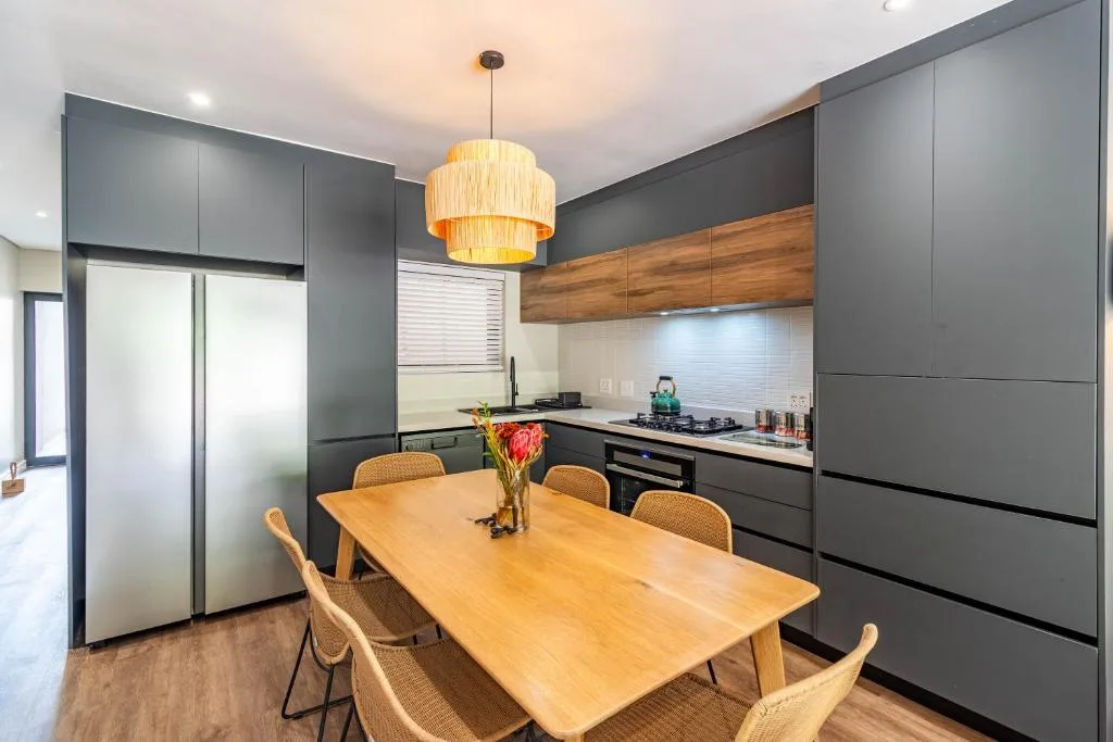 Modern kitchen with dining table, dark cabinetry, and pendant lighting