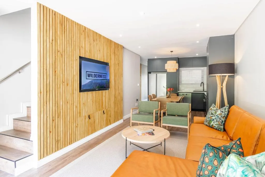 Modern lounge with orange sofa, wooden accent wall, and flat-screen TV