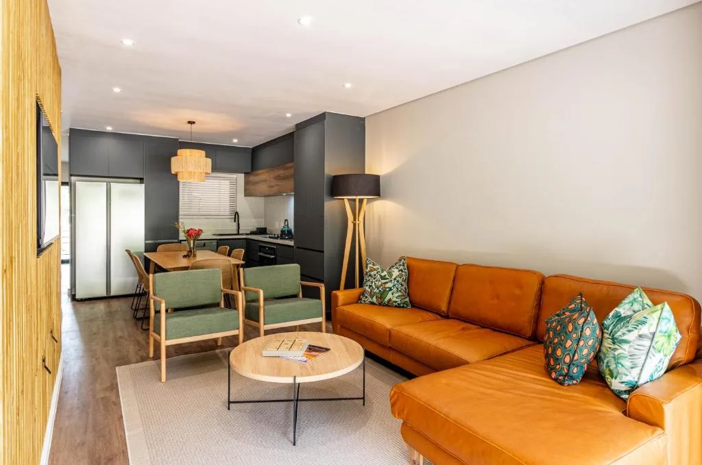 Modern lounge with burnt orange sofa, wooden chairs, and dining area beyond