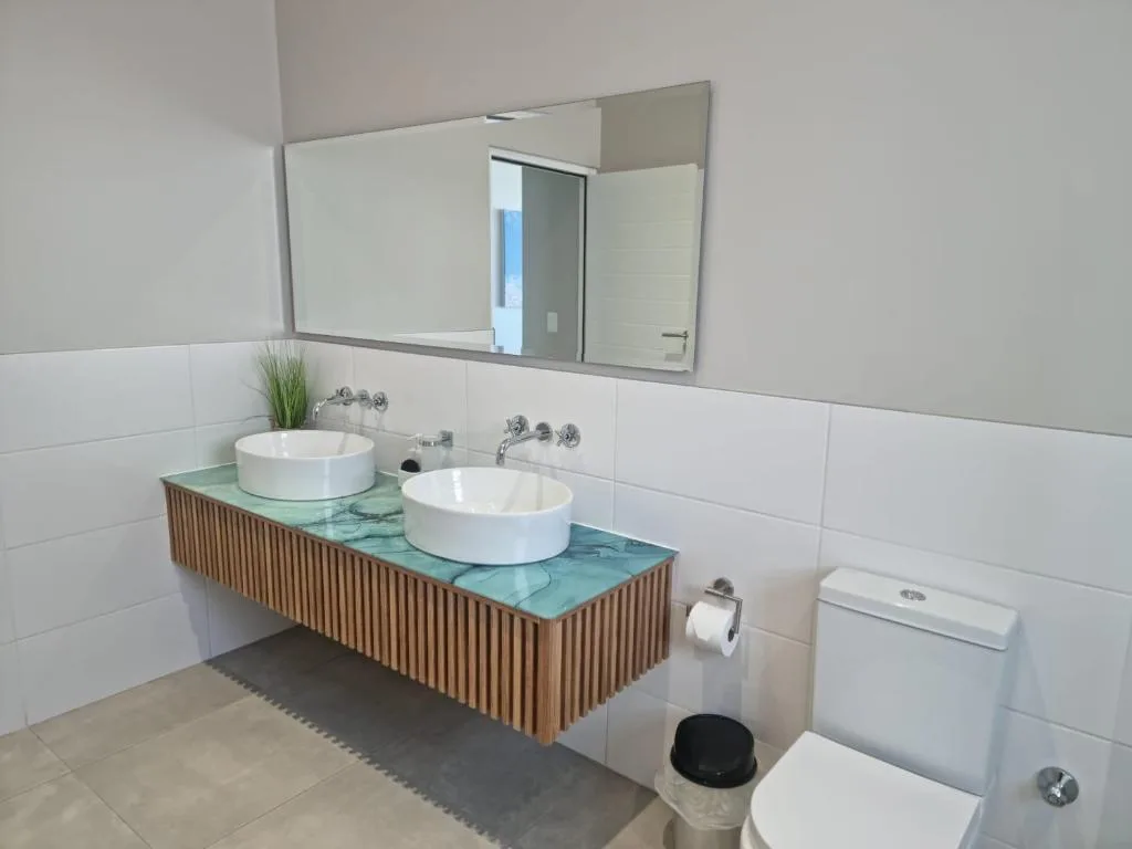 Modern bathroom with dual vessel sinks, large mirror, and white tile walls