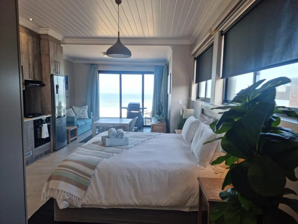 Spacious bedroom with ocean view through large windows and modern amenities