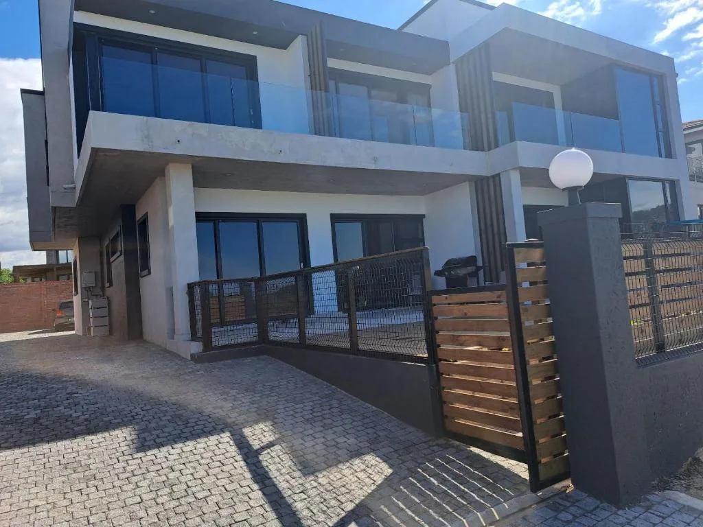 Modern white two-story building with black metal railings and wooden gate entrance