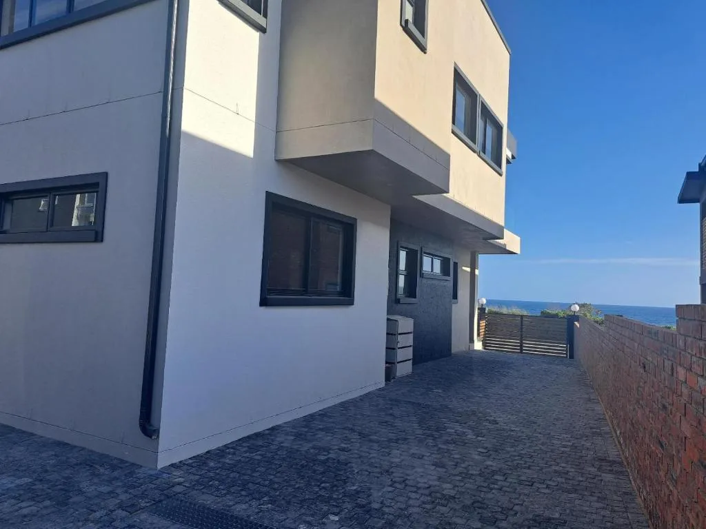 Modern white apartment building with ocean view and brick paved driveway
