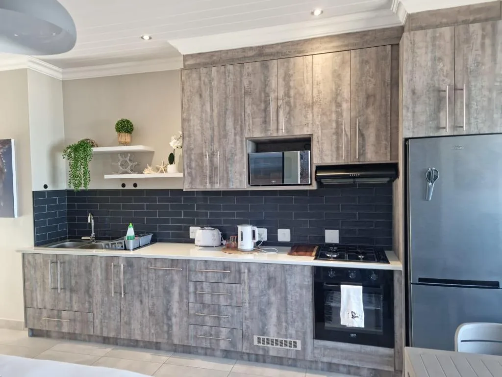 Modern kitchen with gray cabinetry, dark tile backsplash, and stainless steel appliances