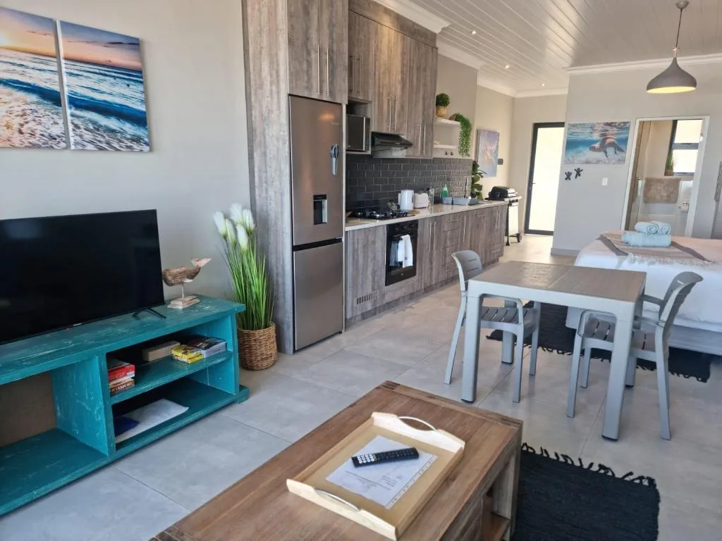 Open-plan lounge with TV, kitchen, and dining area visible in background