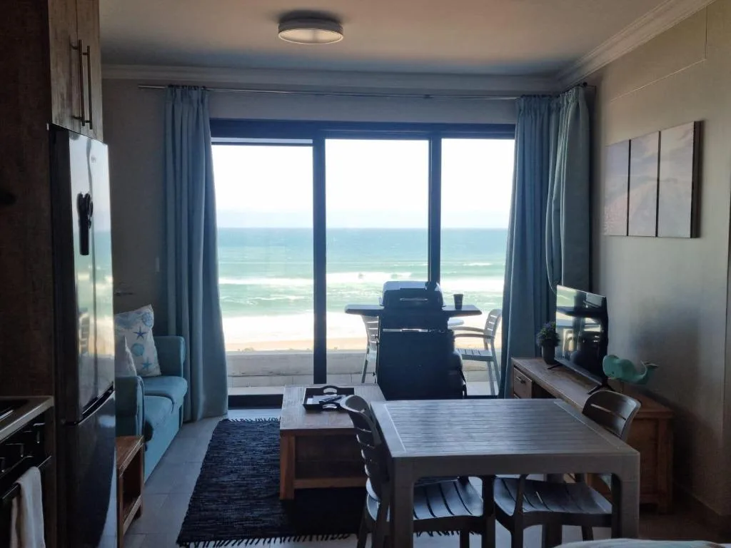Open-plan lounge with ocean view through large windows and sliding doors