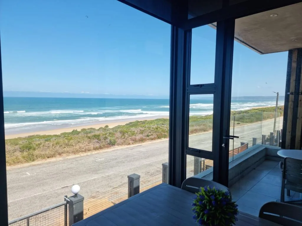 Panoramic ocean and beach view from modern deck with glass doors