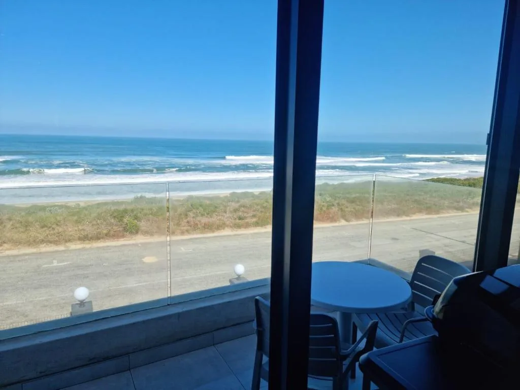 Ocean and beach vista from elevated deck with dining furniture